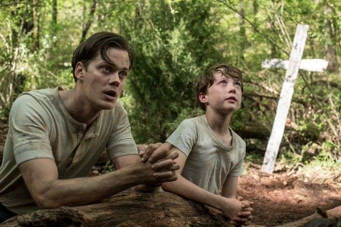 Bill Skarsgard sitting in a park: Netflix's The Devil All The Time