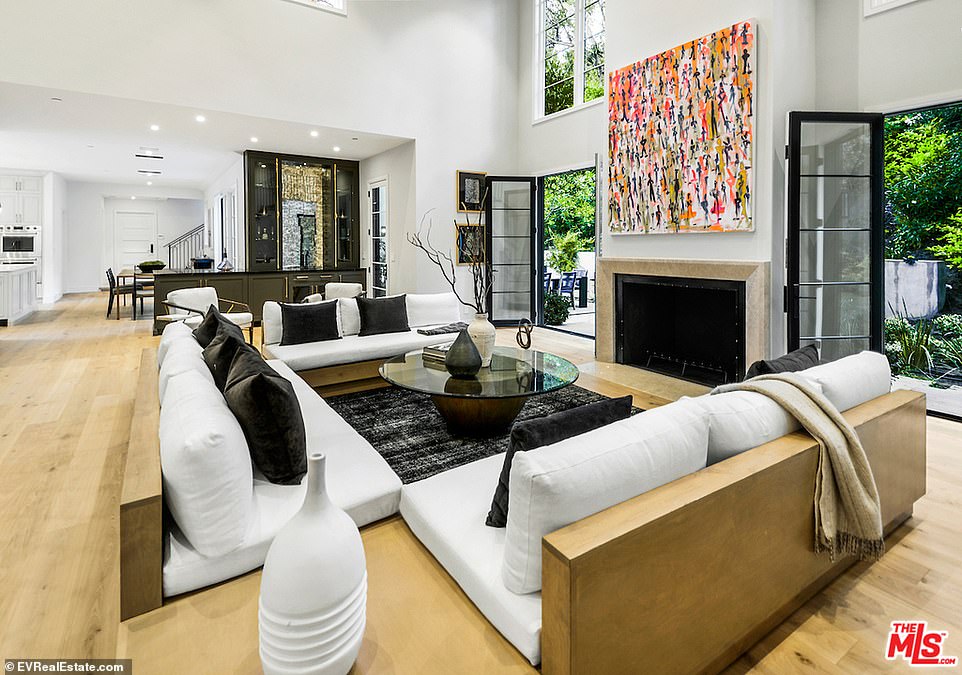 Formal: Two sets of doors are set on either side of a stone-wrapped fireplace, leading inside to a living room just off the kitchen