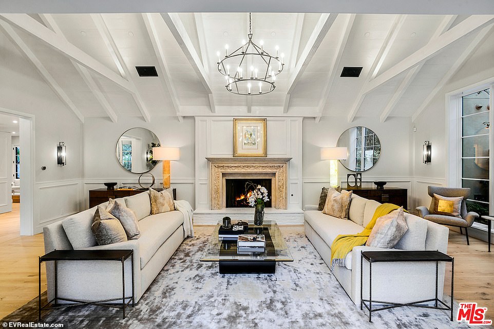 Cozy: Another room, also featured white painted vaulted wood ceilings, a gold framed fireplace, large windows and two couches